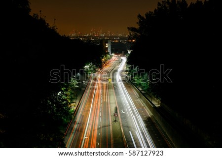 Aerial view of traffic light trails going into London, city skyline on the background.
