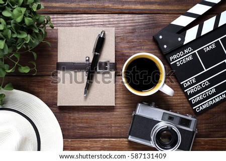 Notebook with coffee and old camera on wood background , top view (concept traveler note)