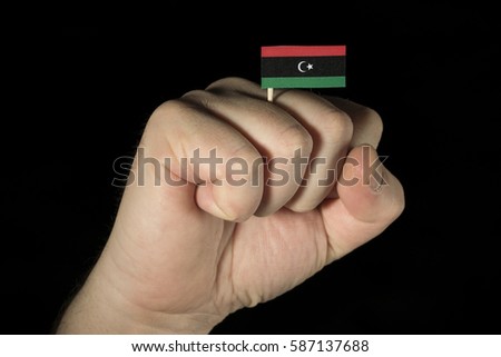 Man hand fist with Libyan flag isolated on black background