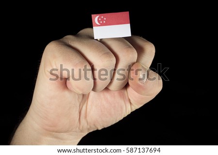 Man hand fist with Singaporean flag isolated on black background