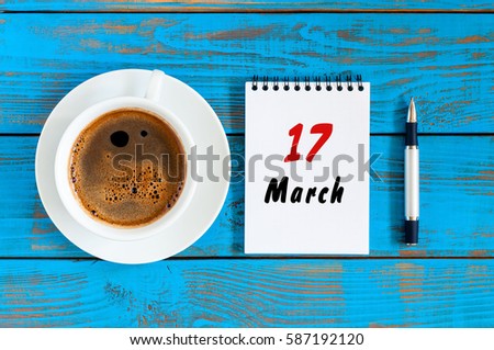 Happy St Patricks Days save the date. March 17th. Day 17 of month, loose-leaf calendar on blue wooden table background with morning coffee cup. Spring time, Top view