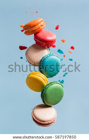 Different types of macaroons in motion falling on light 
blue background. Sweet and colorful french macaroons falling or flying in motion. 