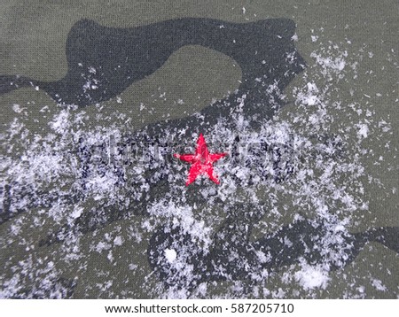 camouflage background with a red star covered with snow                             