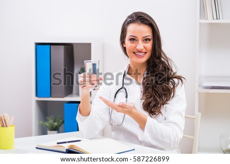 Beautiful female doctor showing that is important to drink water.Female doctor holding glass of water