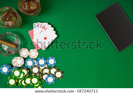 Set to playing poker with cards and chips on green table, top view