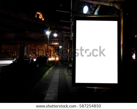 Blank advertising billboard next to bicycle public system at night