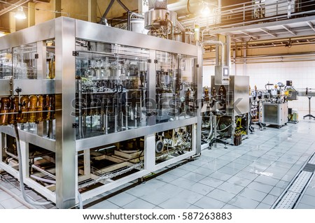 Automatic filling machine. Pouring beer in a brewery. Spot light effect Royalty-Free Stock Photo #587263883