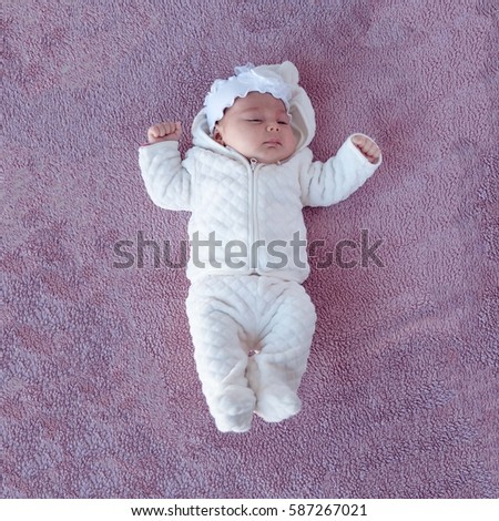 Newborn baby  on a purple background, picture from the top.  Newborn. Kid warmly dressed. 