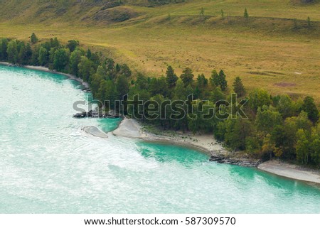 The Katun river in the Altai region in Russia. Mountain cold river. Green fields and forests.