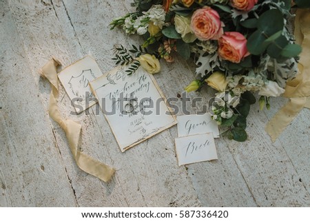 Graphic arts of beautiful wedding calligraphy cards with flower and chiffon bobbins on wood background. Beautiful wedding invitation. Details from fabric, polygraphy and flowers, top view.