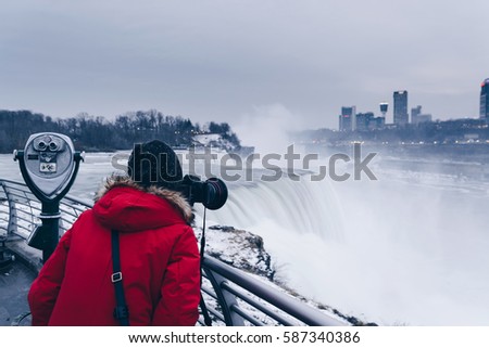 Female photographer taking pictures of Niagara Falls on a cold day 