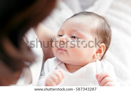 Mother with her newborn baby. Mother is holding her little baby girl.  Photo with soft natural light, with selective focus.