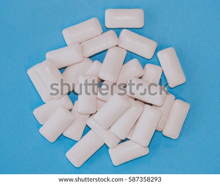 Group of pieces of white chewing gum on a blue pastel background.