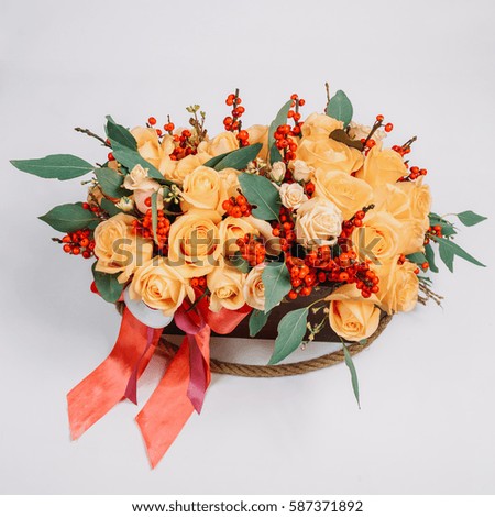 Look from above at yellow roses and red berries put in wooden box