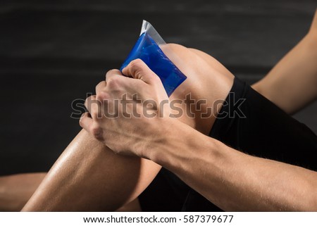 Close-up Of A Person Applying Ice bag On An Injured Knee In The Gym