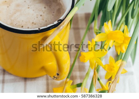 Spring flowers daffodils with a cup of coffee, cappuccino and close-up