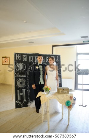 Wedding couple stands behind little white table with chest