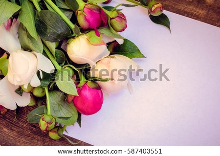 Peony background. Fuchsia, pink and white peonies on old wooden table with an empty sheet of paper for text. Happy Mothers Day. Mother's Day greetings card. Valentines Day. Copy space. Toned image.