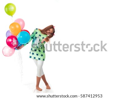 Young girl with long hair in a green tunic with a star with balloons posing on a white background in studio