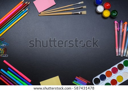The frame of school supplies (pencils, paints, paper, brushes, markers) on a blackboard.