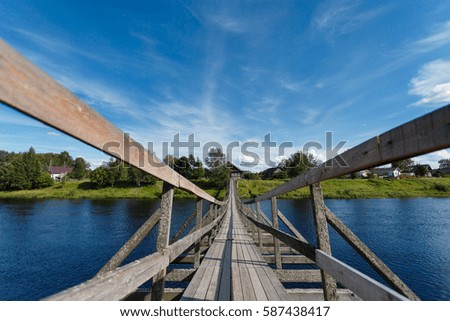 Wooden bridge stretching into the horizon across the river to the other side to the village
