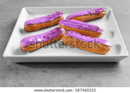White tray with delicious glazed eclairs on light textured background