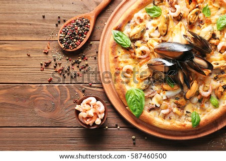 Delicious pizza with seafood on wooden background