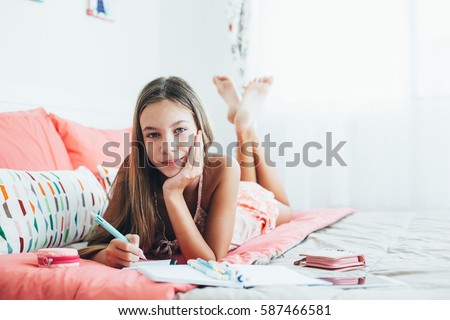 10-12 years old pre teen girl writing diary in pink bedroom Royalty-Free Stock Photo #587466581