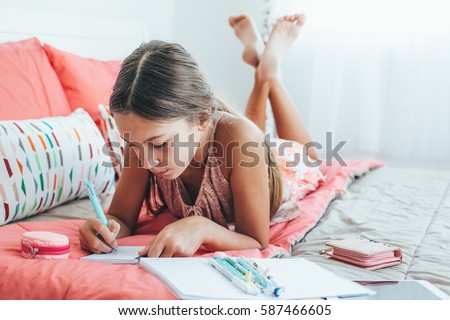 10-12 years old pre teen girl writing diary in pink bedroom Royalty-Free Stock Photo #587466605