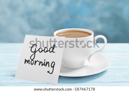 Note with phrase GOOD MORNING and cup of coffee on table
