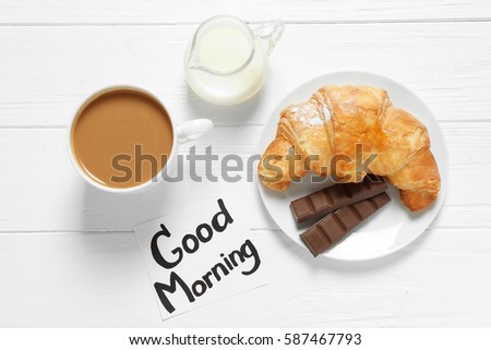 Note with written phrase GOOD MORNING and tasty breakfast on table
