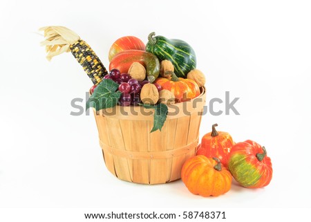 Still picture of Pumpkin, corn and grape in a bushel basket Traditional symbols of Thanksgiving Day and Fall  - horizontal orientation, over white.