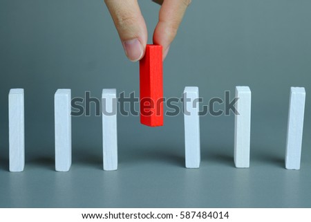 Man hand pick one of red wood block from many white wood block in row, metaphor to business concept in choose idea person from many candidate and different on gray background, selective focus. Royalty-Free Stock Photo #587484014