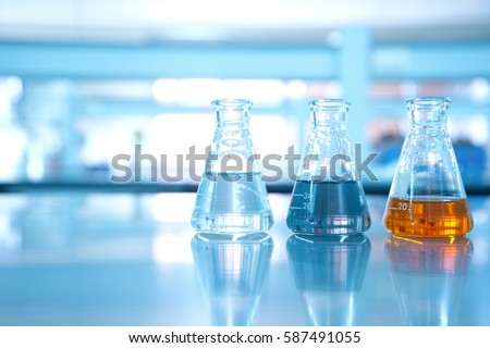 three flask of water black orange solution in science laboratory background Royalty-Free Stock Photo #587491055