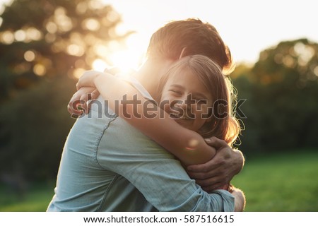 Smiling little girl hugging her father outside Royalty-Free Stock Photo #587516615