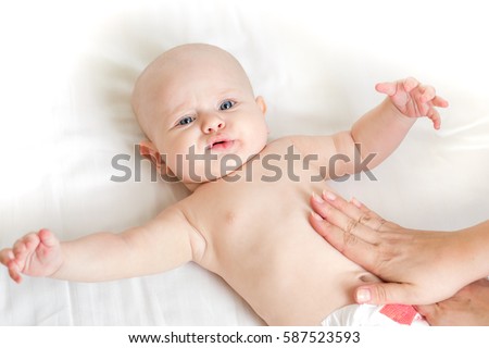 Baby massage lying on the back at home on the bed Royalty-Free Stock Photo #587523593