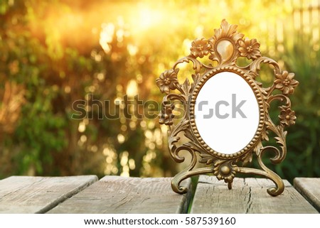 Image of vintage antique classical frame on wooden table outdoors at afternoon. selective focus