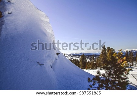 Winter landscape of mountains. Blue sky and green trees. Siberian cold.