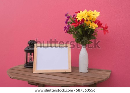 photo Frame on a wooden and Flowers in jar and Lantern on pink background .