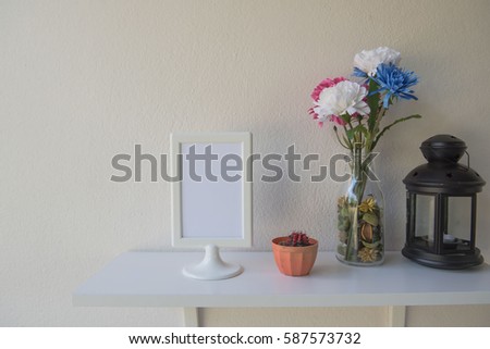 photo White Frame on a wooden and Flowers in jar , cactus, Lantern on wall background .