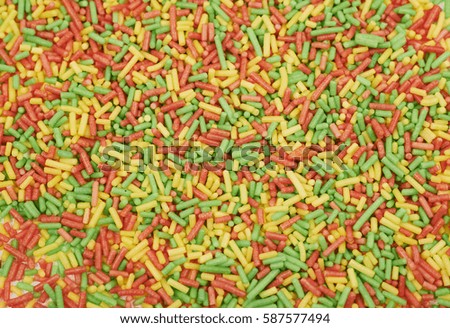 Surface coated with the multiple colorful long sugar candy sprinkles as an abstract background composition