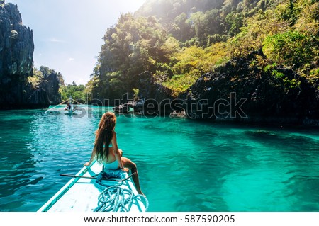 Back view of the young girl relaxing on the boat and looking at the island. Travelling tour in Asia: El Nido, Palawan, Philippines. Royalty-Free Stock Photo #587590205