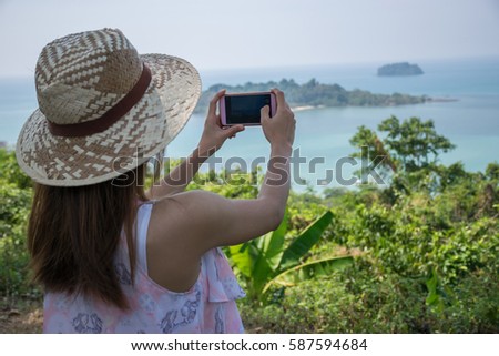 Beautiful Asian girl taking a photo by her smart phone at the viewpoint while her traveling.
