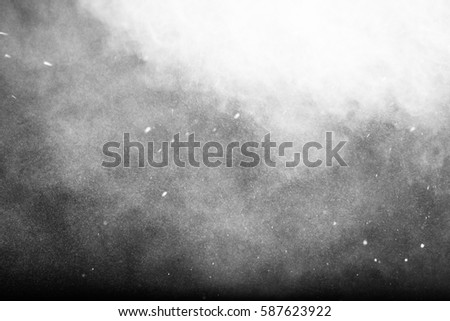 Freeze motion of white powder exploding, isolated on black, dark background. Abstract design of white dust cloud. Particles explosion screen saver, wallpaper with copy space. Planet creation concept