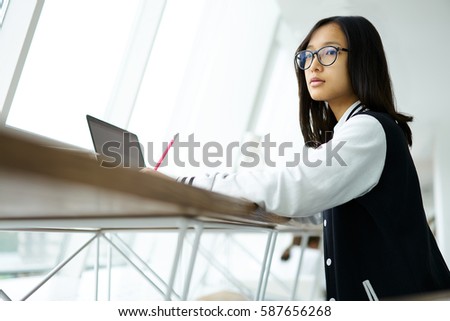 Concentrated young teenage girl thinking over creating composition for hometask  using laptop computer connected to wireless internet  to finding information get inspire of silence in classroom