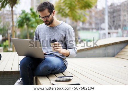Concentrated male freelancer editing photo files chatting with employer discussing requires for project working on own schedule during break in university using  laptop computer and wireless internet