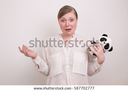 beautiful girl on a light background with a toy Panda with a surprised face