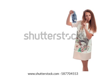 Sweet girl with long hair in a pink dress with a soft toy rabbit in the hands posing on a white background in studio