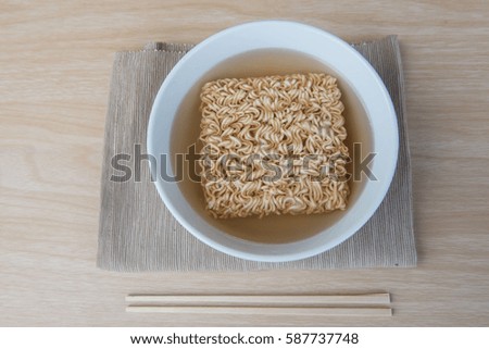 Top view Instant noodles in white dish and chopsticks on wood background.