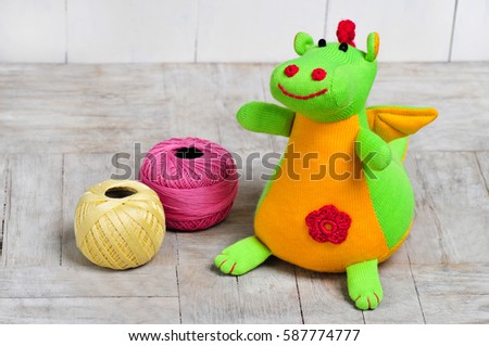 Knitted dragon isolated on wooden background.